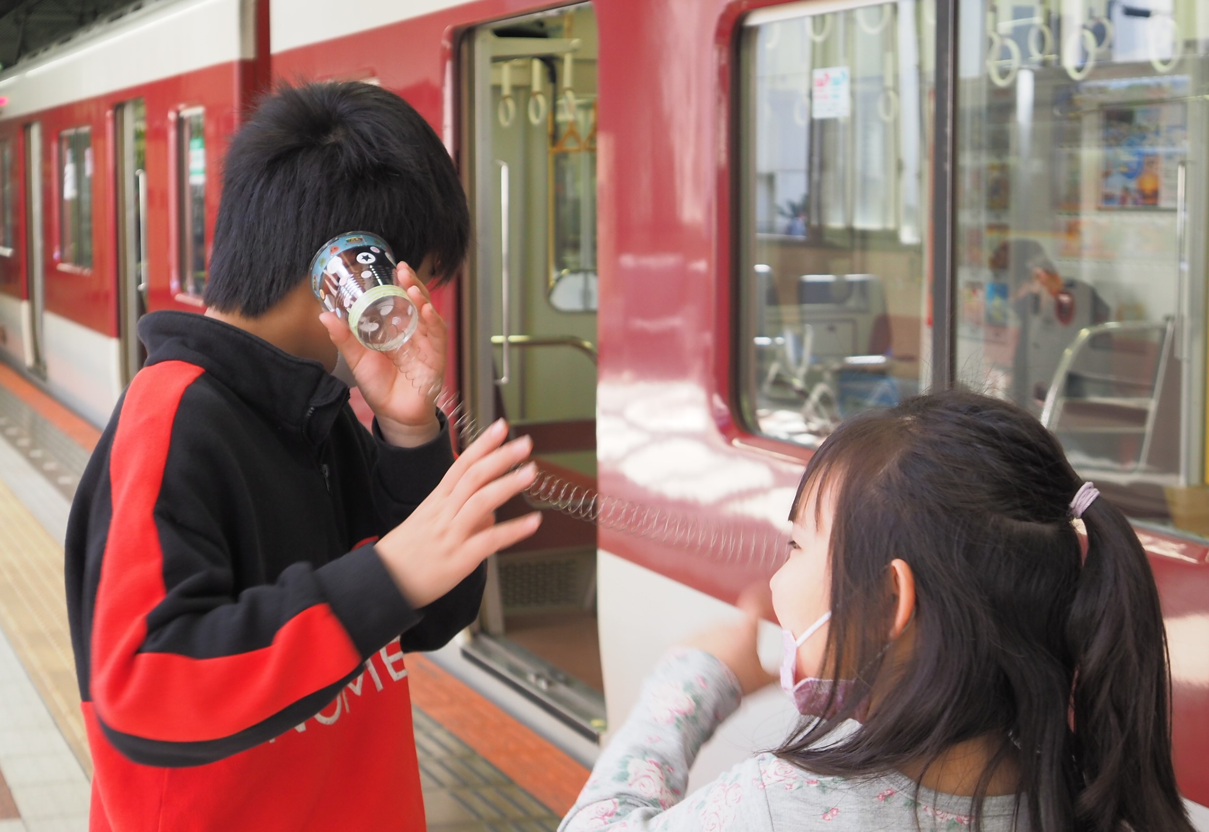 ばね電話で遊ぶ子どもたちの写真