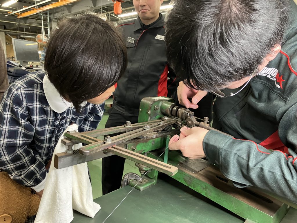 ギアでばねを巻く様子を見守る女の子