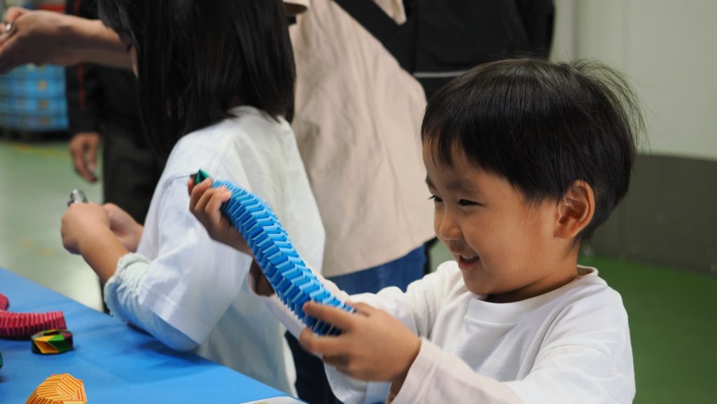 紙製のばねを伸縮させて遊ぶ男の子